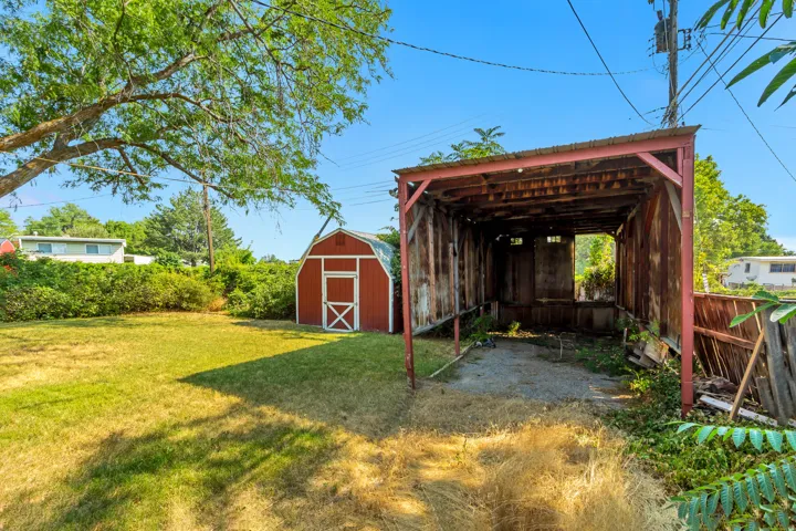 Expansive yard with a red barn-style shed and a covered open-air structure