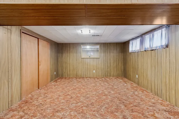Finished room featuring wood-panel walls, carpet flooring, and a drop ceiling with recessed lighting