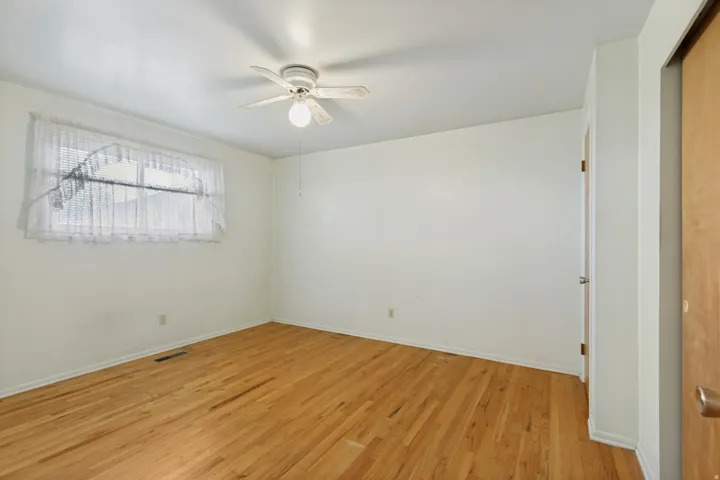 Wood-finish flooring, white walls, and an overhead ceiling fan
