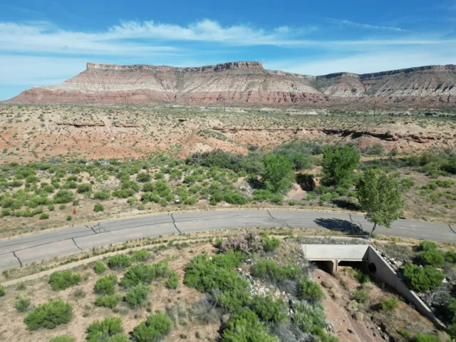 Expansive natural landscape with varied terrain, including distant rock formations and a paved road