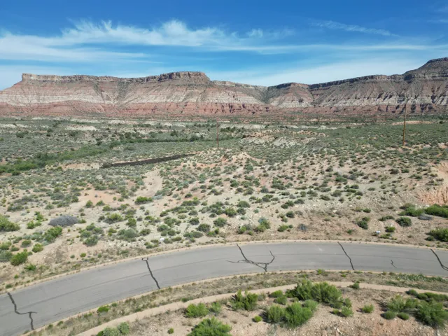 Expansive desert landscape featuring a paved road, natural rock formations, and varied scrub vegetation