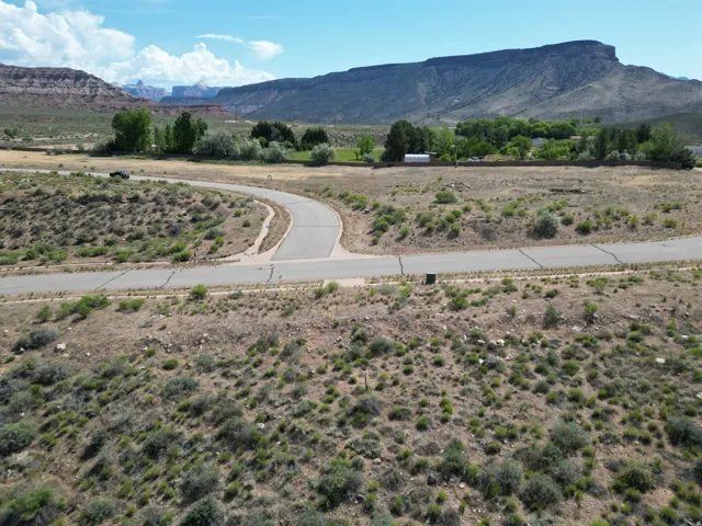 Paved roadway with a cul-de-sac, surrounded by natural desert landscaping and distant mountain formations
