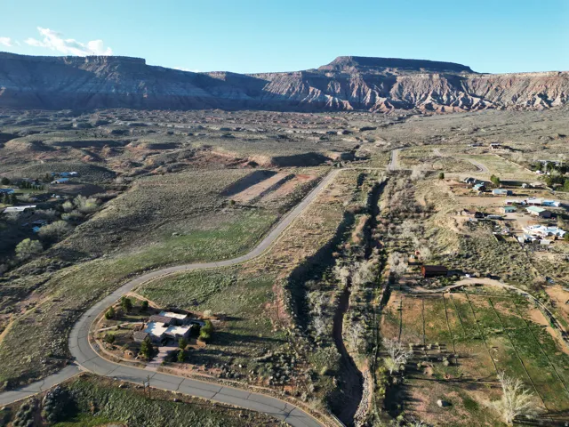 Expansive natural landscape with a prominent mesa backdrop and winding paved roads