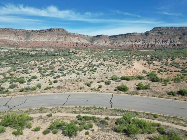 Paved road with desert landscaping and distant mountainous terrain
