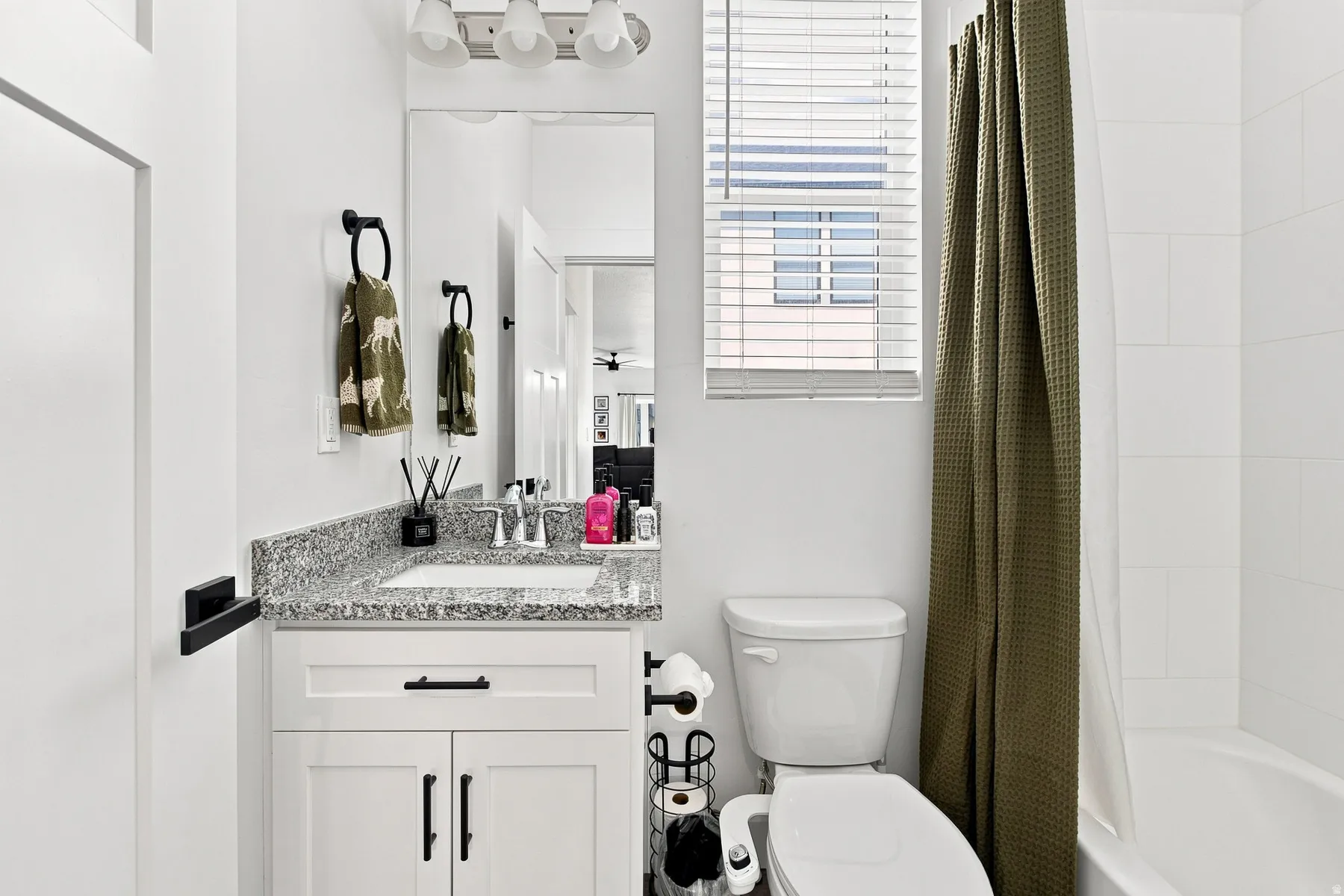White vanity with shaker-style cabinetry, granite-finish countertop, and undermount sink