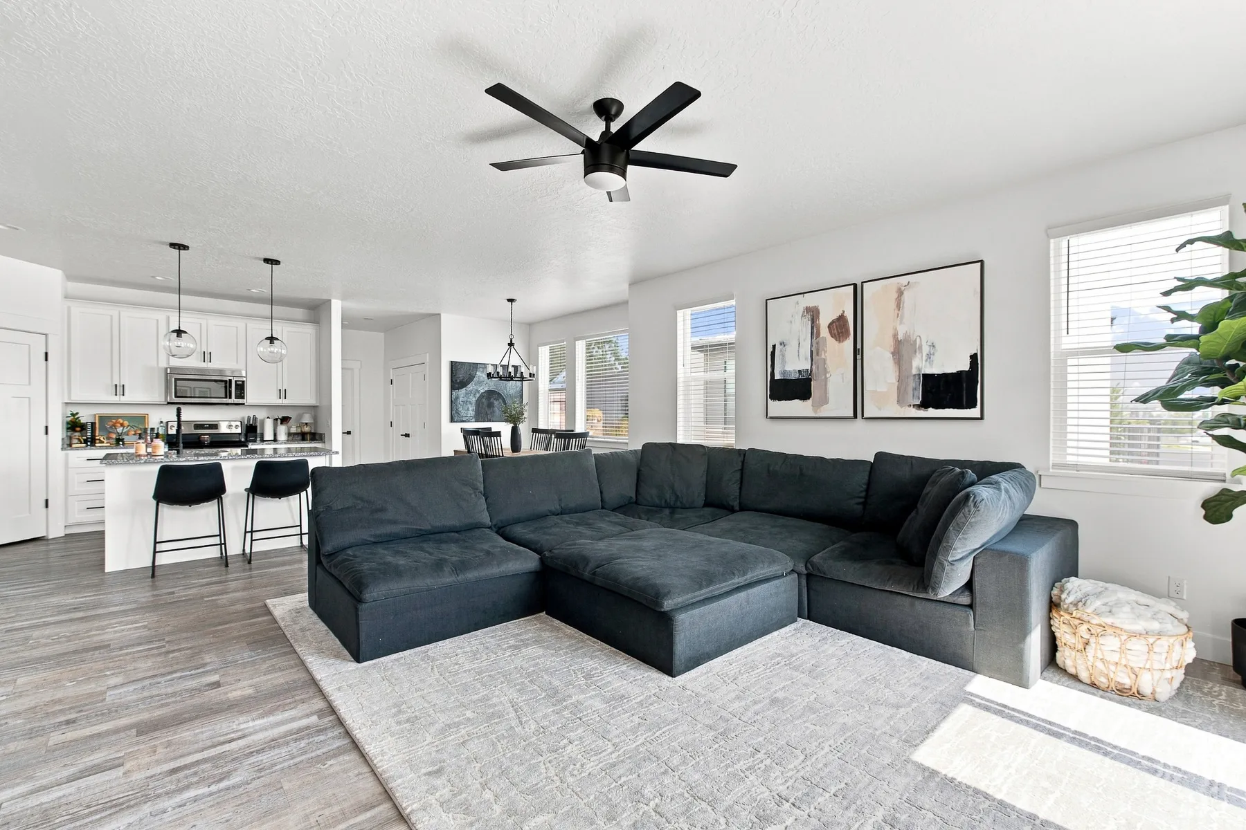 Open-concept living space featuring wood-finish flooring, white walls, and a black ceiling fan
