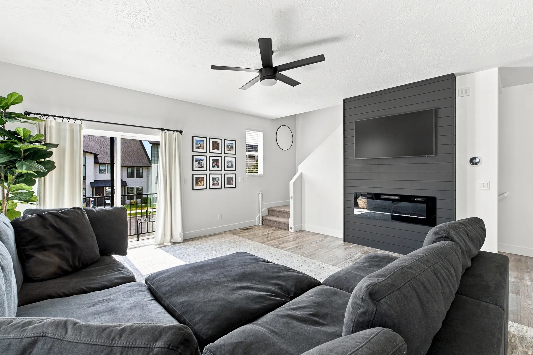 Living area featuring wood-finish flooring, a contemporary ceiling fan, and a built-in electric fireplace
