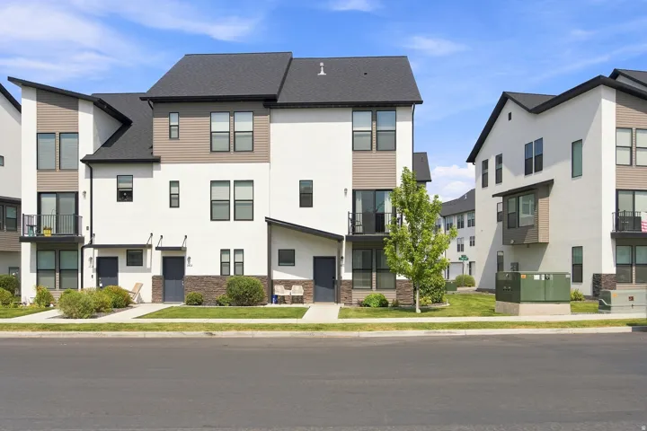 Modern townhome exterior with mixed material facade, black framed windows, dark roofing, and private balconies