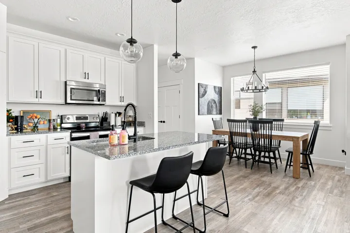 White shaker cabinetry, stainless steel appliances, granite countertops, wood-finish flooring, and recessed lighting