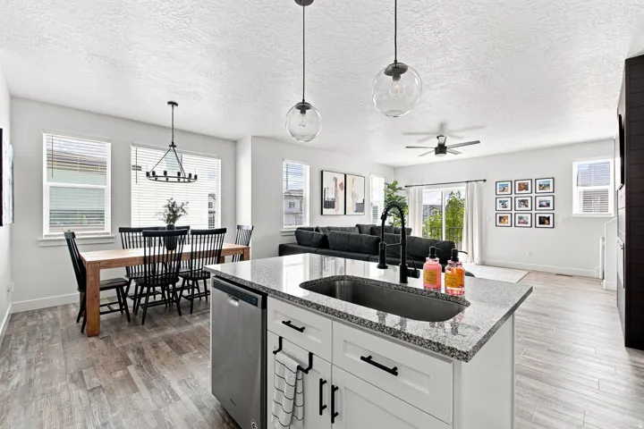 Open-concept living space featuring wood-finish flooring, a kitchen island with granite countertops, and a stainless steel dishwasher