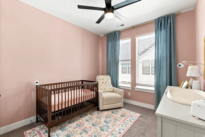 Room with a ceiling fan, two windows with blinds, and carpeted flooring
