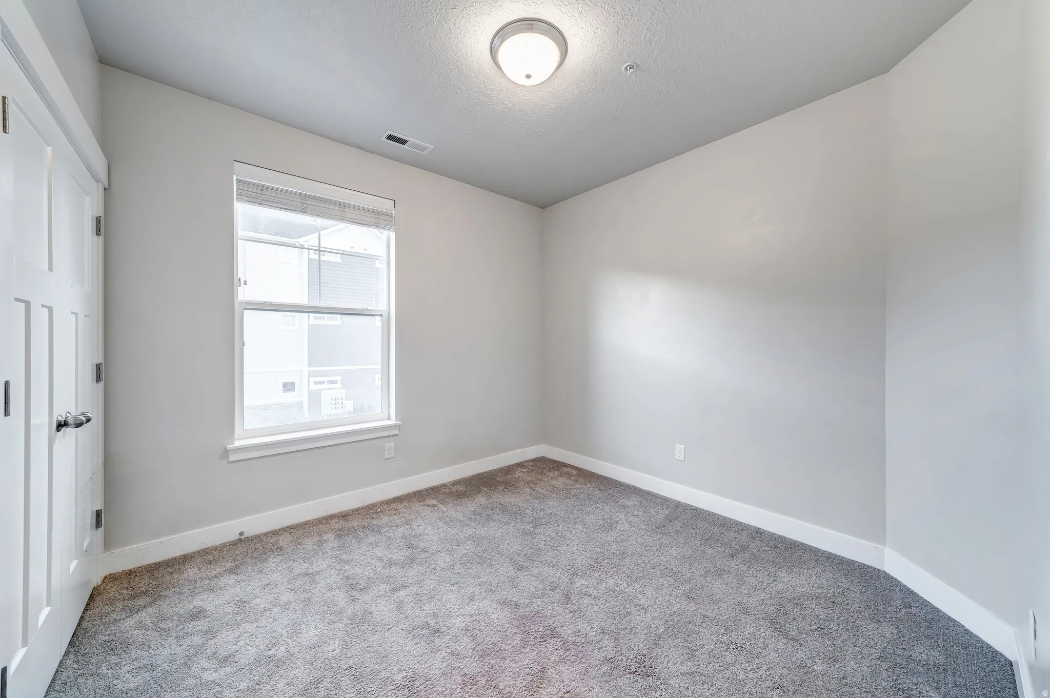Neutral wall finishes, recessed window, paneled interior door, and overhead flush-mount lighting