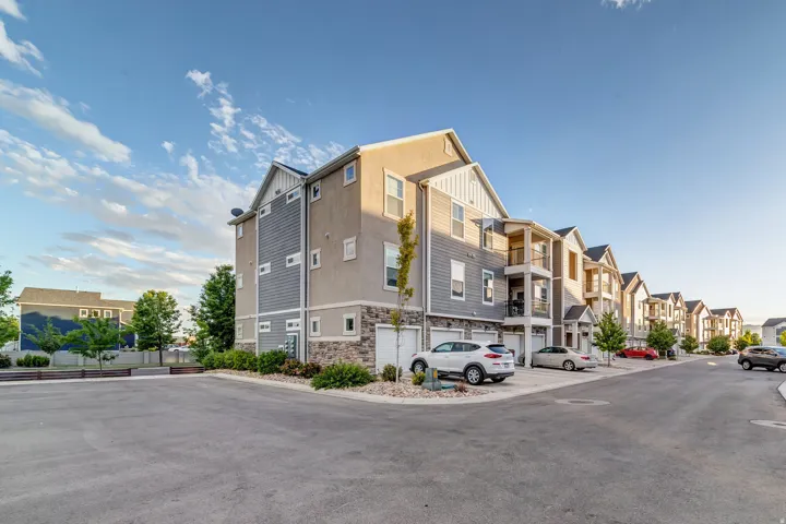 Contemporary multi-story townhome with attached garages, individual balconies, and stone veneer accents