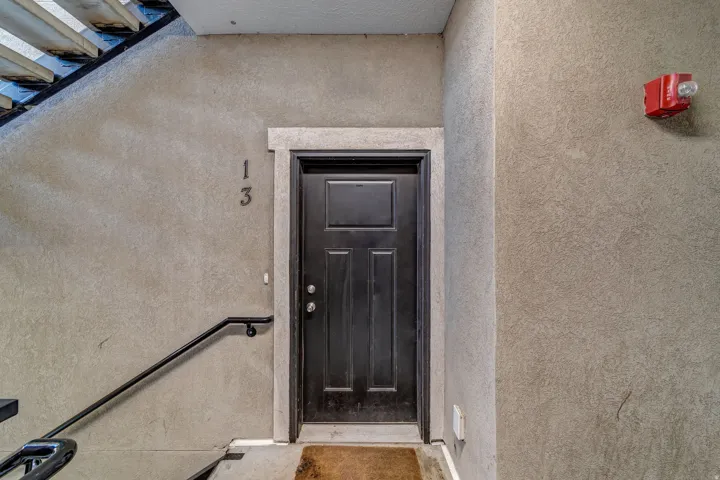 Panel-style entry door with a doorframe, complemented by a metal handrail and textured wall finishes