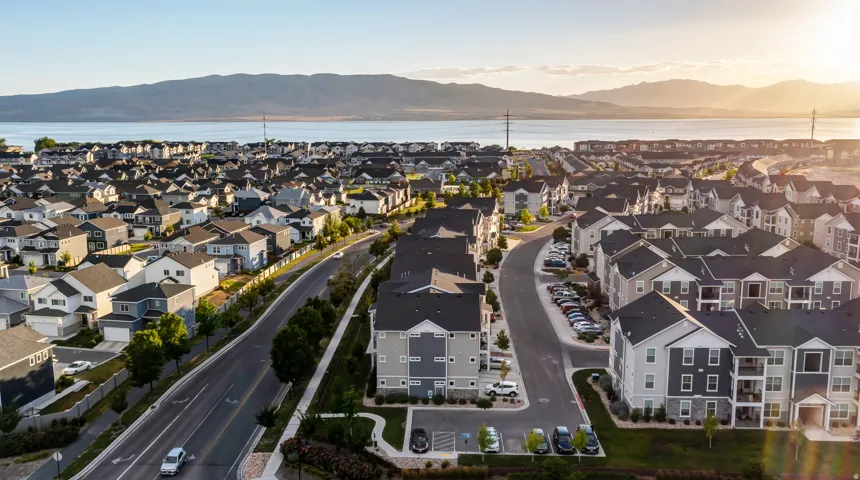 Residential area featuring single-family homes and multi-story buildings, established street system, and distant water body with mountains