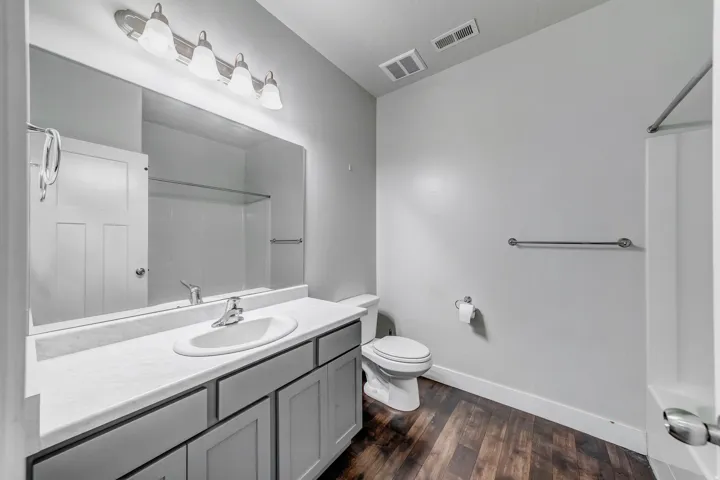 Single vanity with an integrated sink, broad wall mirror, and a five-light fixture
