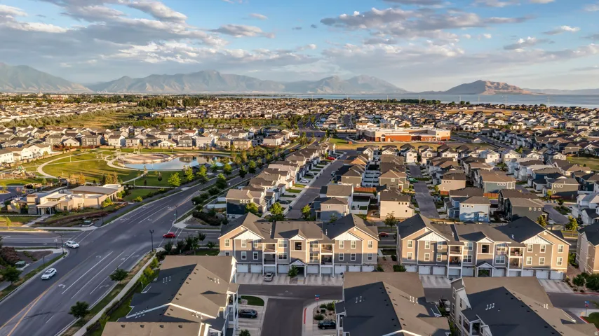 Expansive community featuring residential homes, a park area with a pond, and distant mountains