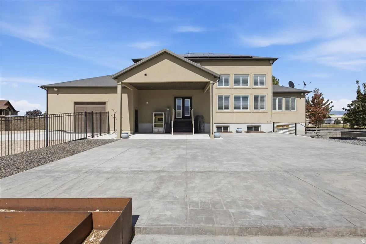 Stucco exterior with multiple windows, covered entry, attached garage, and a concrete driveway