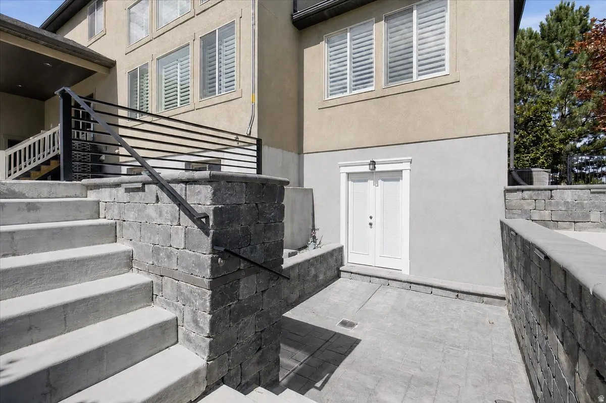 Concrete staircase with a black metal handrail leading to a paved patio area