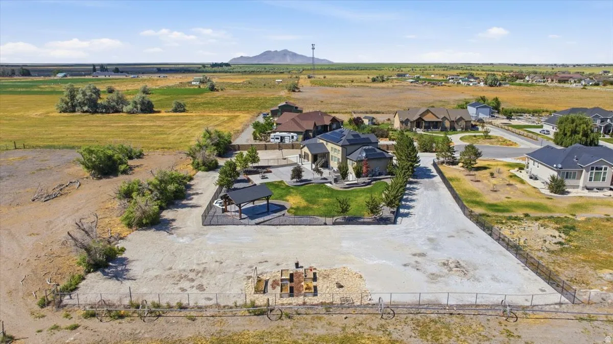 Expansive property featuring a large gravel-covered area, a fenced yard with a gazebo, and mature landscaping surrounding the main residence