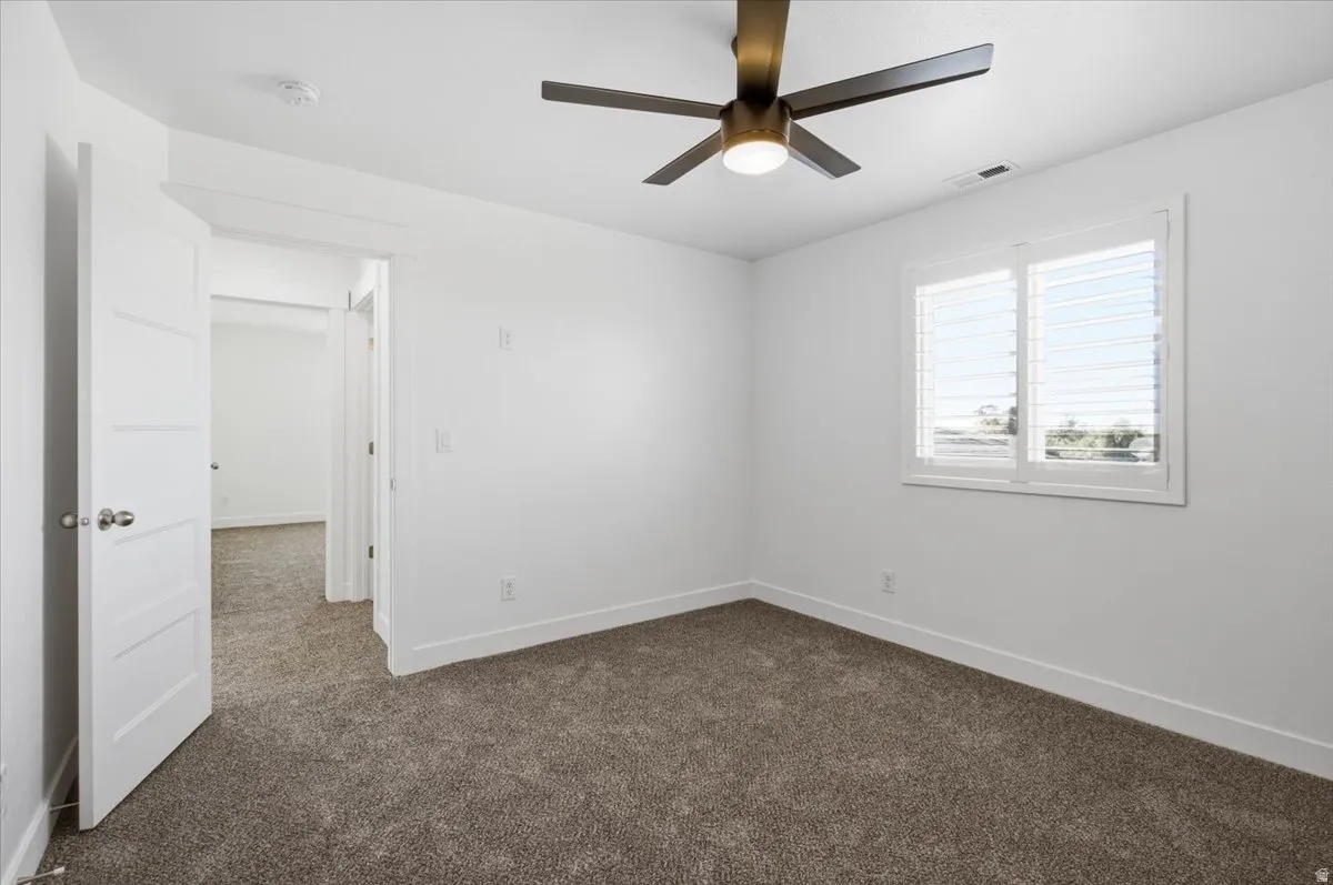 Recessed lighting, ceiling fan with integrated light, plantation shutters, and soft gray carpeting