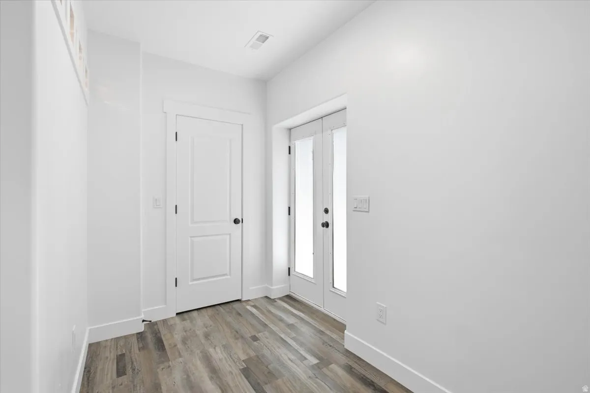 Wood-finish flooring, white walls, and a two-panel interior door with matte black hardware