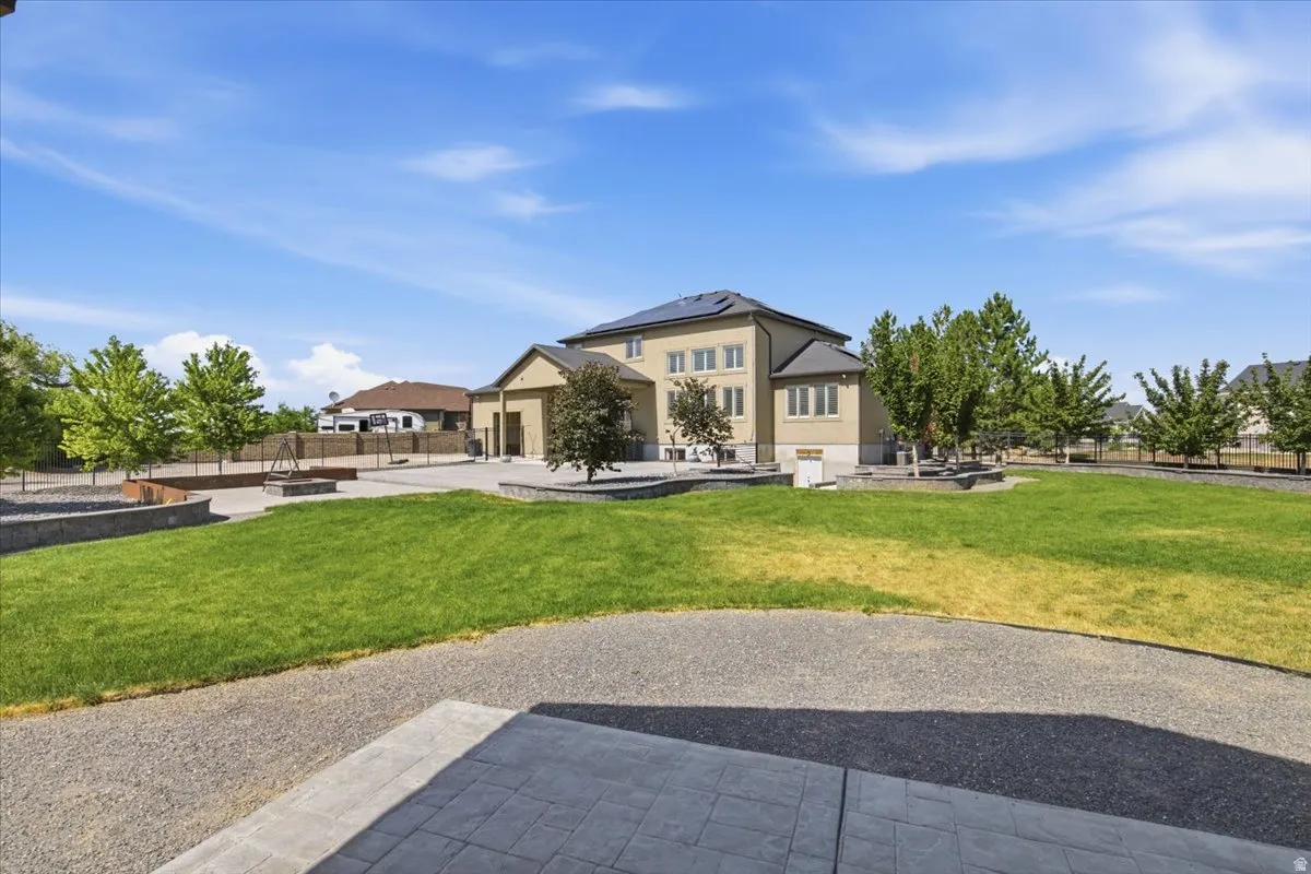 Expansive backyard featuring a large lawn area, mature trees, and a concrete patio