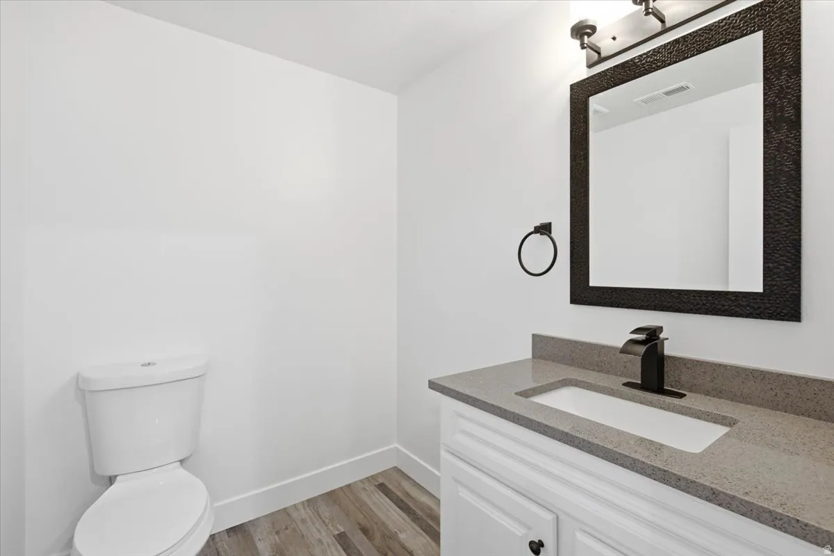White vanity with shaker-style door, gray countertop with integrated sink, black single-handle faucet, and black framed mirror