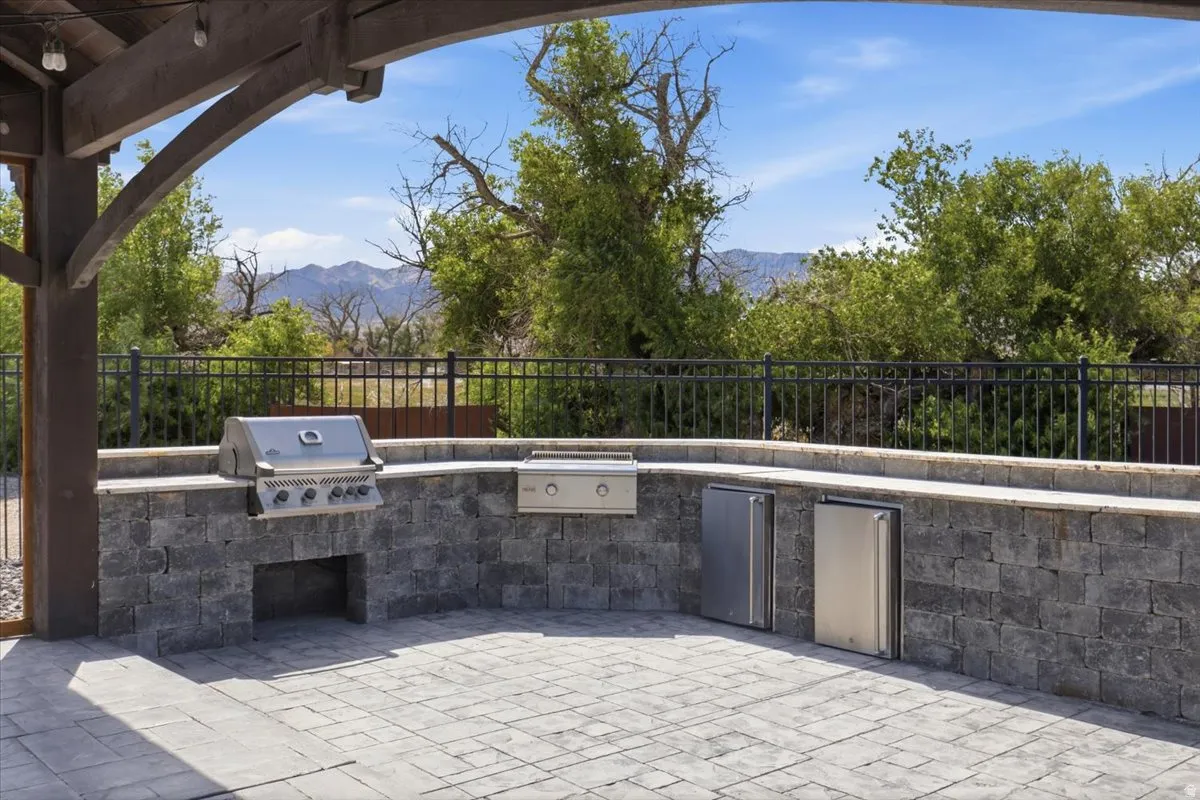Outdoor kitchen featuring a built-in grill, stainless steel appliances, and a stone block base