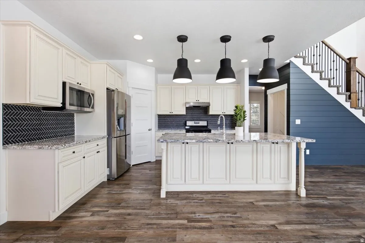 Kitchen featuring white cabinetry, stainless steel appliances, granite countertops, and a herringbone tile backsplash