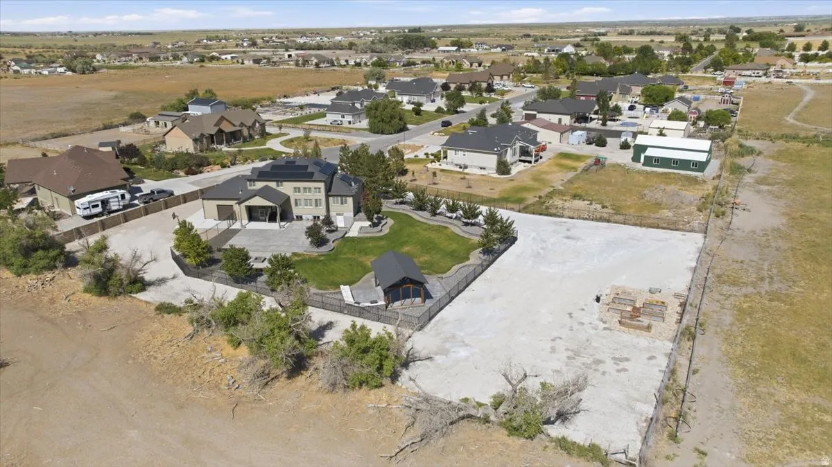 Spacious property featuring a large residence, expansive paved patio, detached shed, and a built-in fire pit area