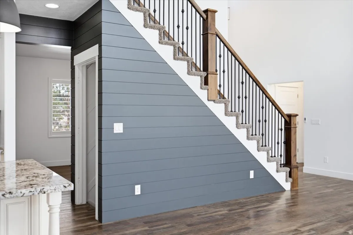 Staircase with wood newel posts, black iron balusters, and carpeted treads
