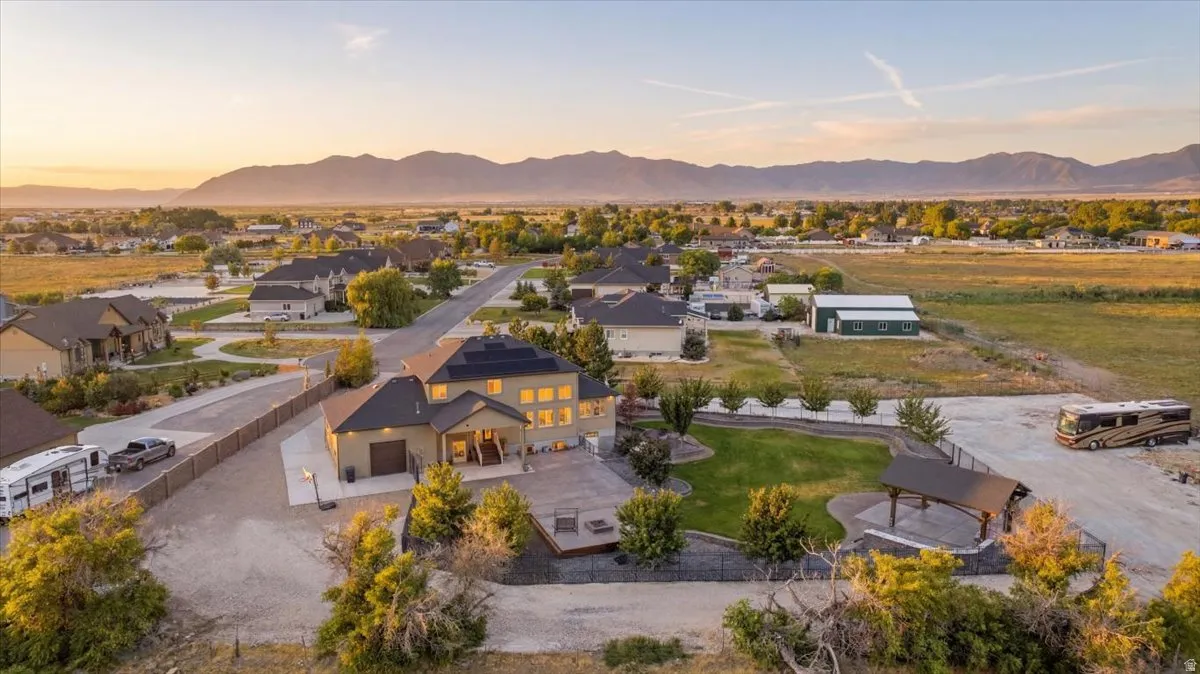 Expansive property featuring a large residence, detached garage, covered patio, and extensive paved and gravel areas