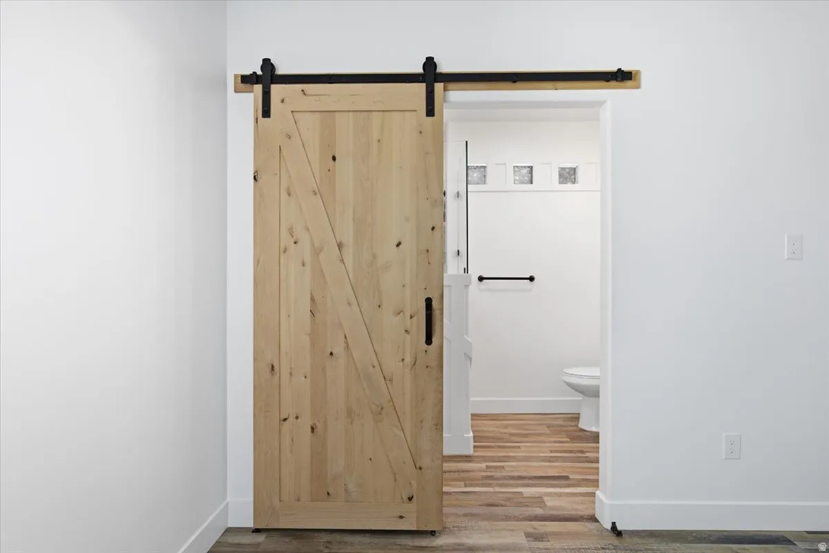 Natural wood barn door with black hardware, white walls, and wood-finish flooring