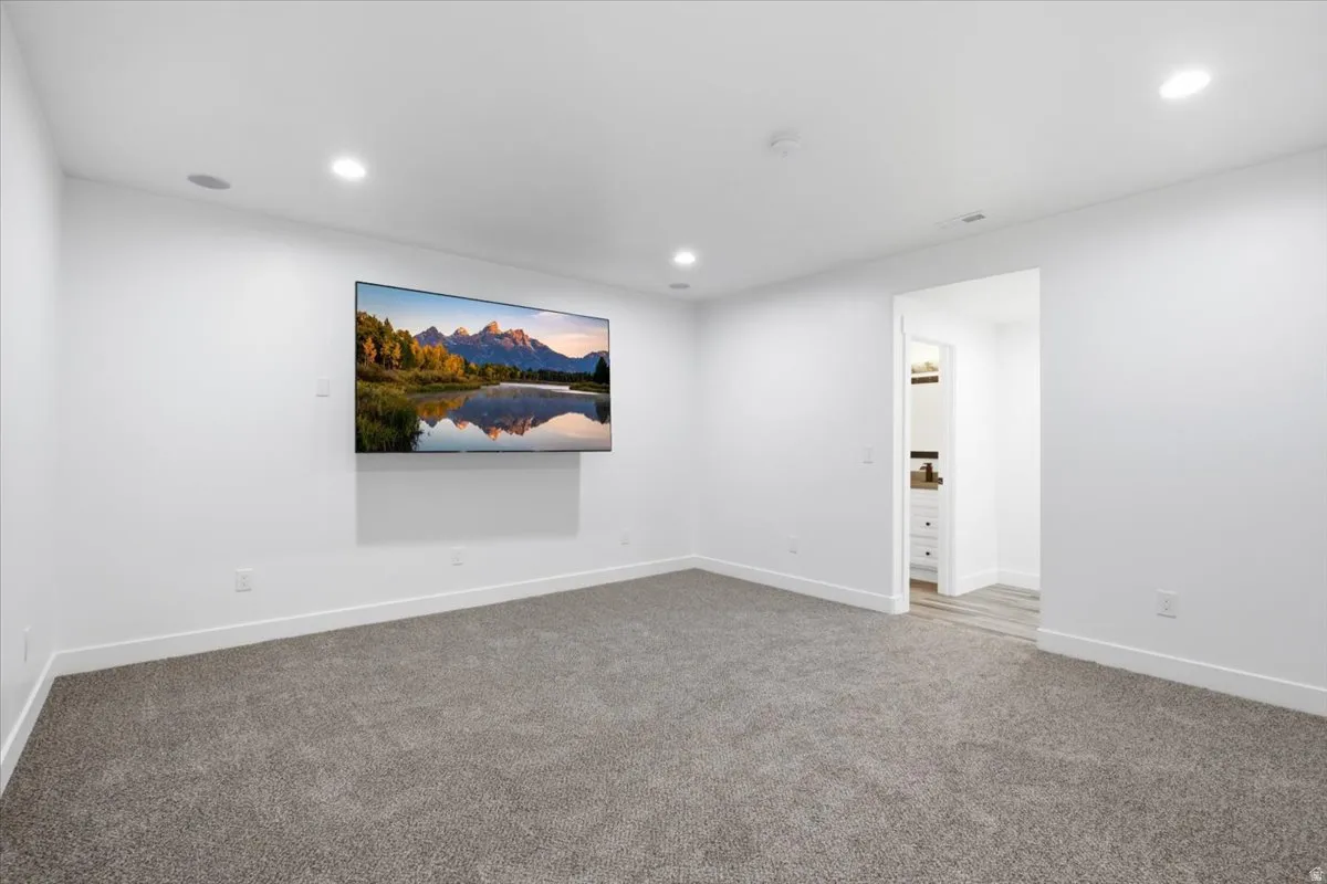 Recessed lighting, wall-mounted television, and speaker system with neutral carpeting