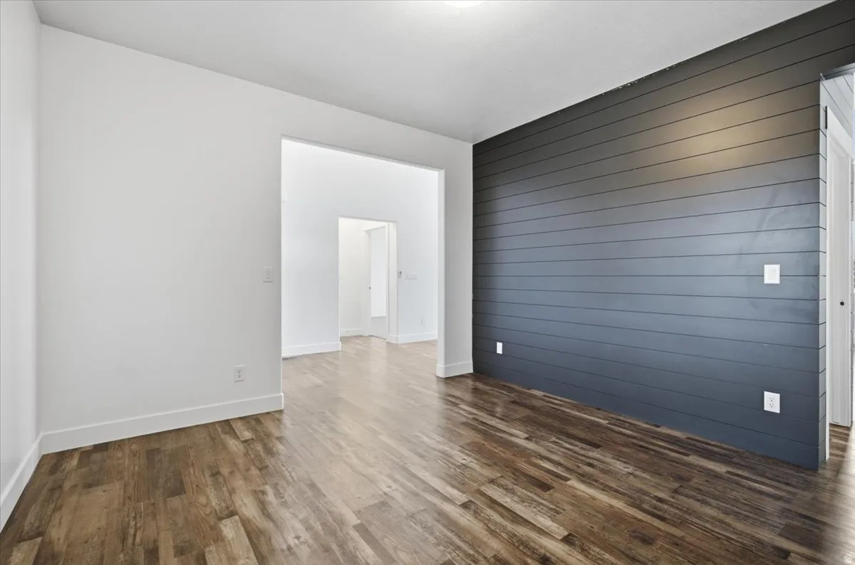 Wood-finish flooring, white wall finishes, and a dark accent wall with horizontal paneling