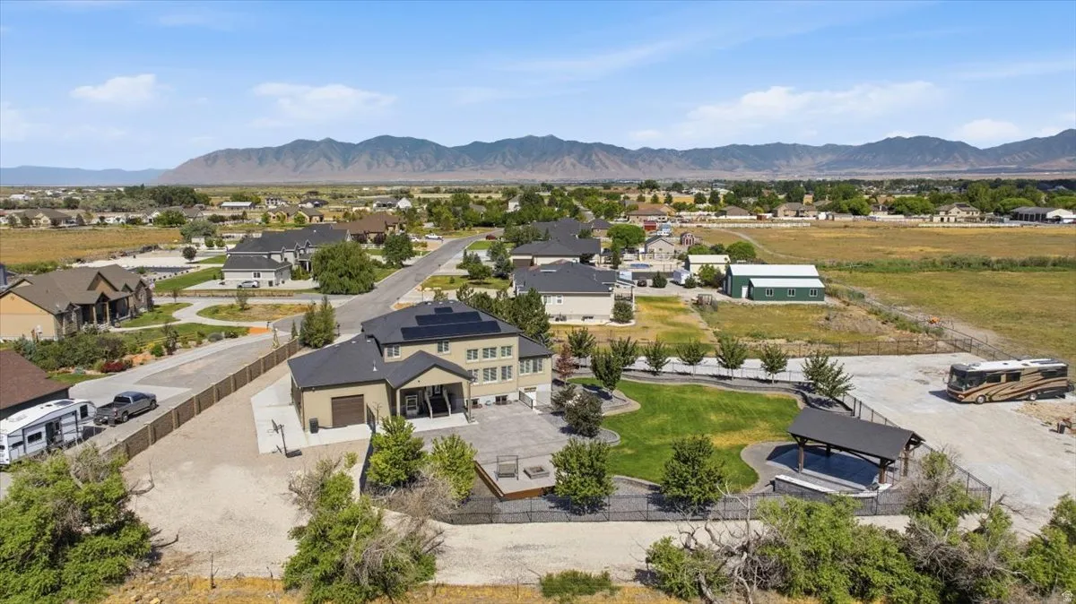 Expansive property featuring a large lawn, covered patio, dark fencing, and mature landscaping