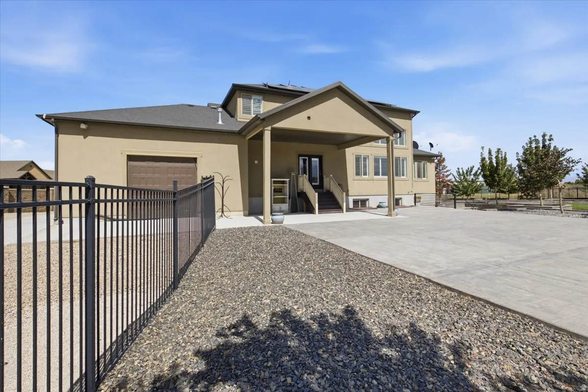 Extensive concrete driveway, covered porch entry, stucco exterior, and a dark brown garage door