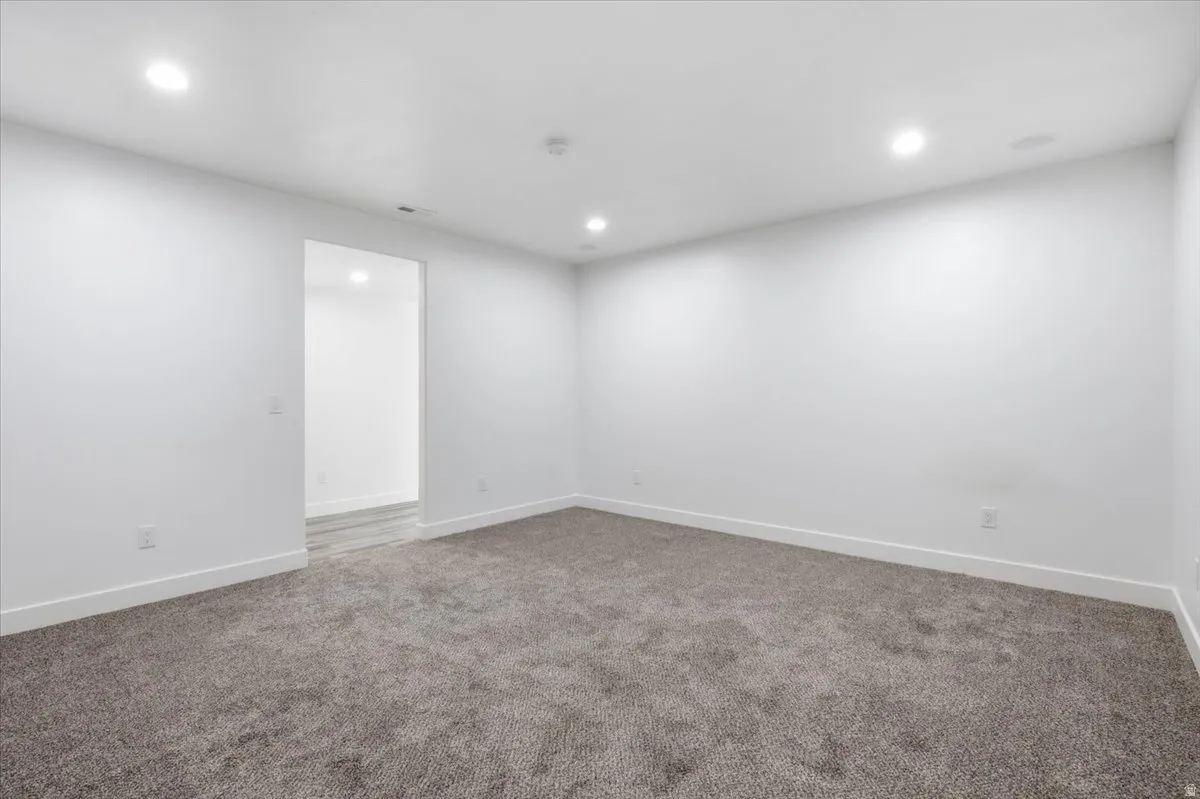 Recessed ceiling lighting, white walls, gray carpeting, and white trim