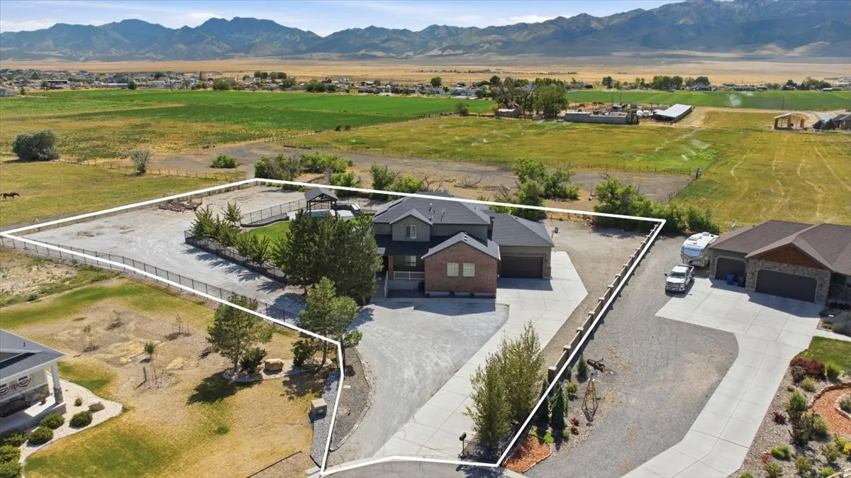 Two-story exterior with brick and siding facade, attached two-car garage, and expansive gravel driveway