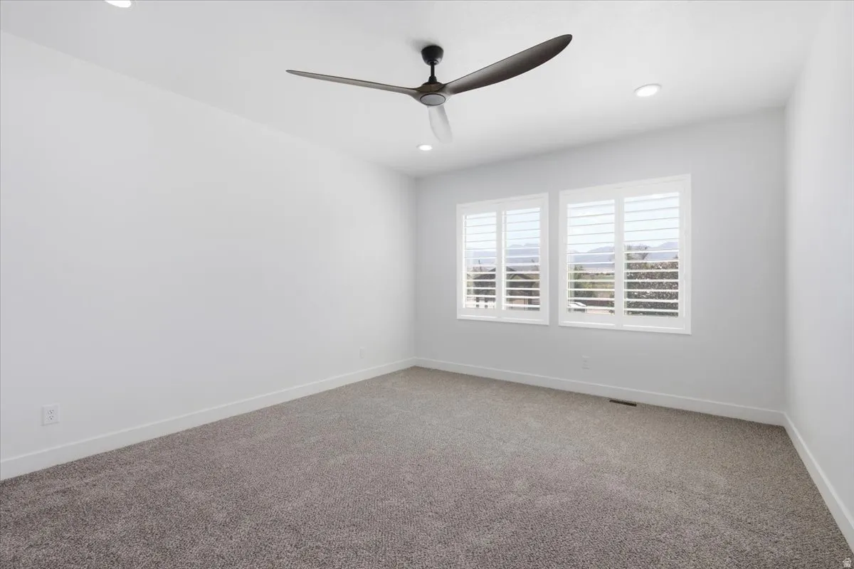 Recessed lighting, ceiling fan, white walls, carpeted flooring, and white window shutters
