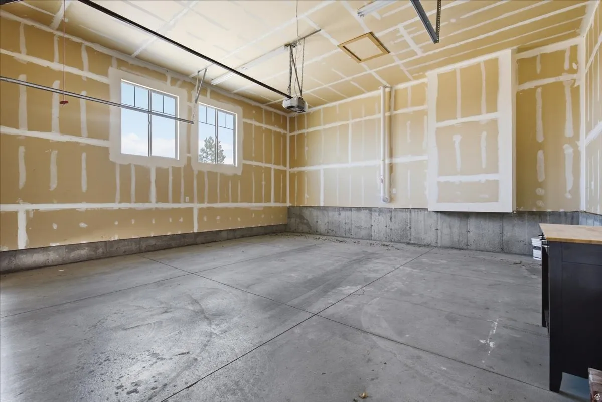 Two double-hung windows, exposed drywall, concrete flooring, and an automatic garage door opener system