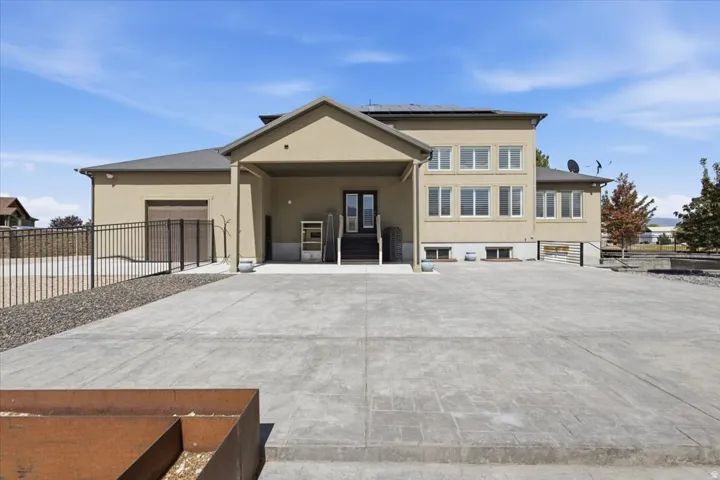 Stucco exterior with multiple windows, covered entry, attached garage, and a concrete driveway
