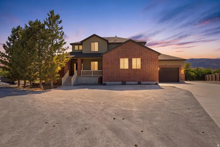 Brick and stucco exterior with multiple windows, an attached garage, and a covered porch