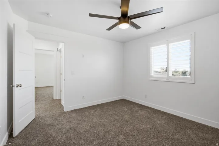 Recessed lighting, ceiling fan with integrated light, plantation shutters, and soft gray carpeting