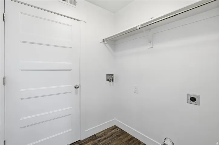 Laundry area featuring wood-finish flooring, white walls, and a built-in shelving unit with hanging rod