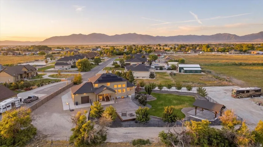 Expansive property featuring a large residence, detached garage, covered patio, and extensive paved and gravel areas