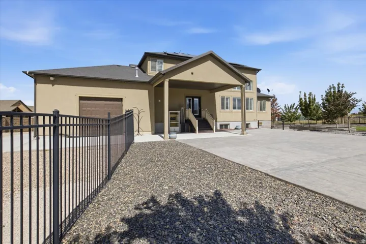 Extensive concrete driveway, covered porch entry, stucco exterior, and a dark brown garage door