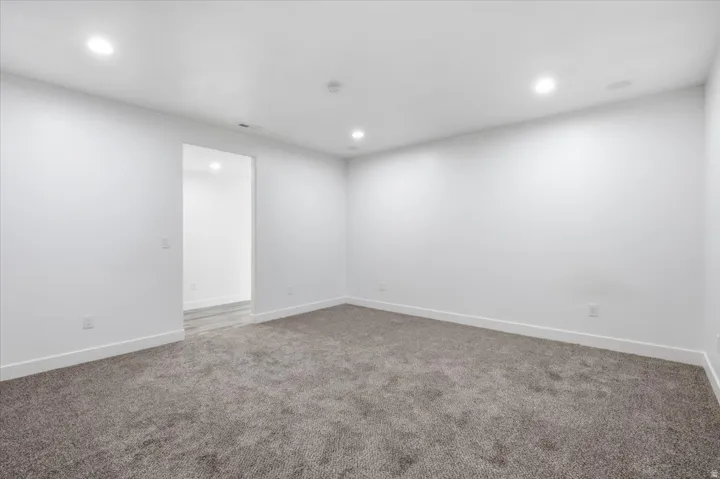 Recessed ceiling lighting, white walls, gray carpeting, and white trim