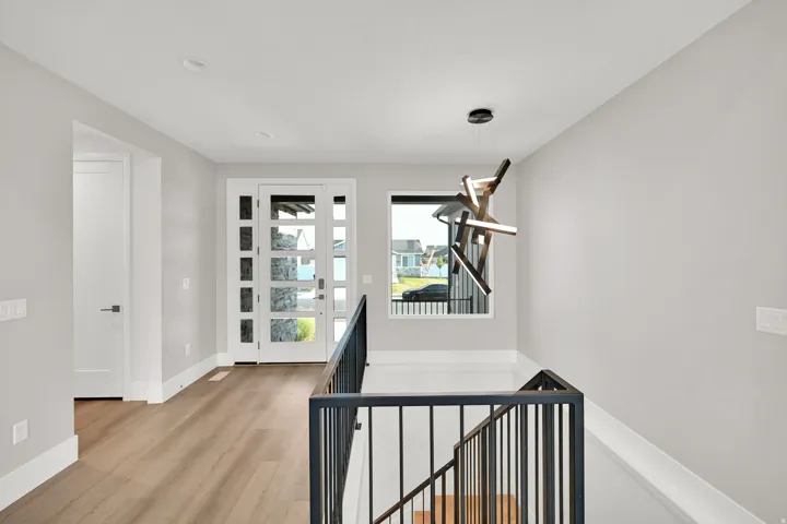 Bright second-floor landing featuring hardwood flooring, white painted walls, and black metal stair railing with horizontal spindles